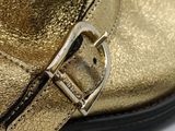 a close up of a gold boot with a buckle on it