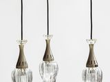 trois suspensions en verre suspendues au plafond dans une pièce blanche
