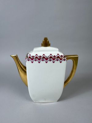 an image of a white teapot with a gold handle and a red and white design