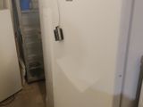 Plusieurs réfrigérateurs blancs sont alignés dans une pièce sans portes
