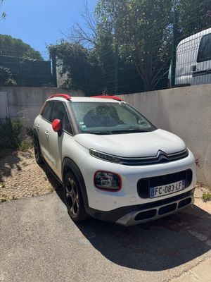 la petite voiture blanche est garée sur le bord de la route