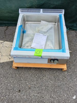 un petit congélateur posé sur une palette au sol