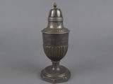 a silver vase with a bell on top on a gray surface
