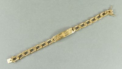 gros plan d'un bracelet en or sur une surface grise