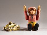 a toy monkey sitting next to a toy tank on a white surface