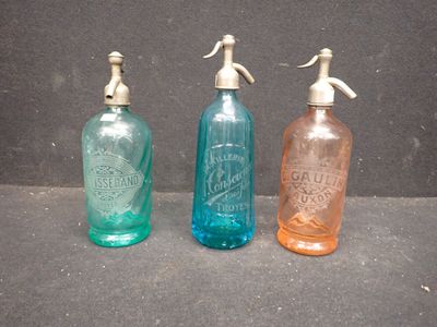 trois bouteilles en verre de couleurs différentes posées les unes à côté des autres