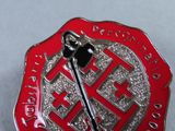 a red and silver fire department badge with an axe on it