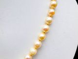 yellow pearl necklace on mannequin display with black background