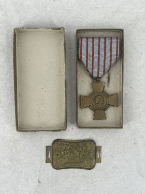 medal in a box with a ribbon and a tag on a white surface