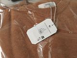 a brown sweater with a tag on it sitting on a table