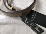 a belt that is laying on a bed with a tag attached to it