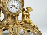 a gold clock with cherensils and angels on it