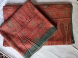 a red and green scarf laying on a bed