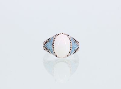 une bague en oplite blanche et topaze bleue sur un fond blanc