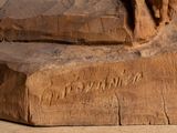 a wooden carving of a dog laying on a rock