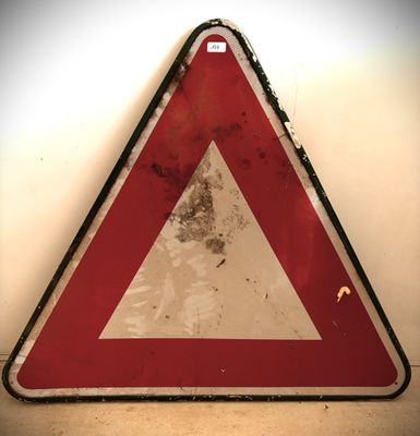 un panneau triangulaire rouge et blanc sur un mur blanc
