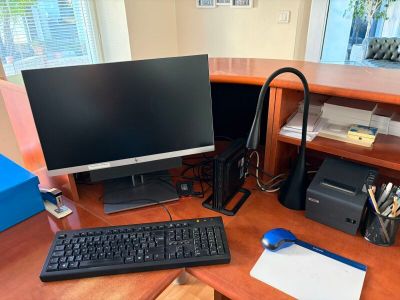 a desk with a computer, keyboard, mouse and printer on it