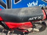 un cyclomoteur rouge garé devant un mur bleu