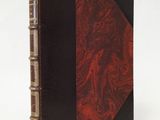 an old book with a red cover sitting on top of a table