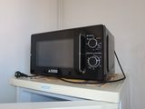 a black microwave sitting on top of a white refrigerator