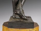 bronze statue of a woman sitting on a pedestal with her legs crossed