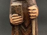 wooden figurine of a monk holding a book and smiling