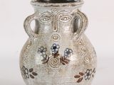un vase blanc avec des fleurs sur une surface blanche