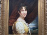 portrait d'une femme en robe jaune devant un rideau rouge