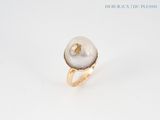 an image of a white pearl and gold ring on a white surface