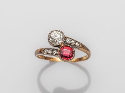 un gros plan d'une bague sertie d'un diamant rouge et blanc sur une surface blanche