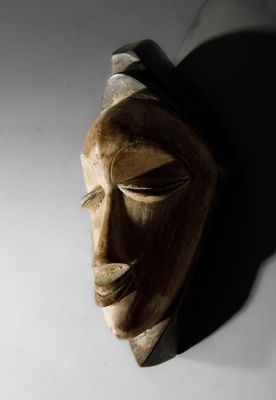 un masque en bois accroché à un mur dans l'obscurité