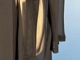 the back of a black coat with a tan shirt and black pants