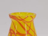 a yellow and red vase sitting on a white surface
