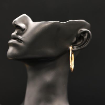 a close up of a mannequin head with a pair of gold hoop earrings