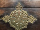 an antique brass cross on a wooden table with a black background
