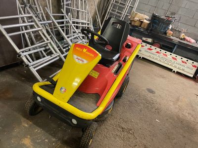 yellow and red lawn mower sitting on top of a pile of chairs