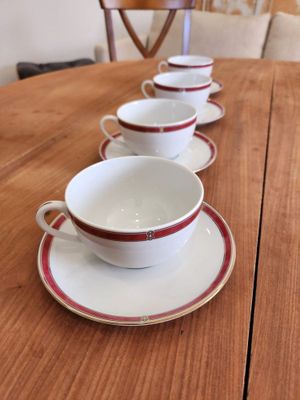 several cups and saucers are lined up on a wooden table