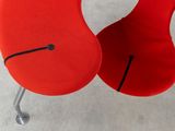 a red chair with a black seat and a black foot rest