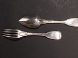 two silver spoons and a fork on a table