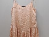 pink top with ruffles on hanger against white wall