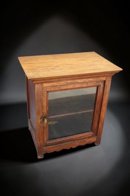 une vieille armoire en bois avec une porte vitrée sur fond noir