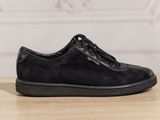 the black shoe is on a wooden table with a white wall in the background