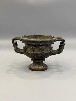 une image représentant un vase en bronze posé sur une surface blanche