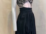 Le mannequin porte une jupe noire et un haut court.