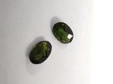 two green tourmaline gems on a white surface