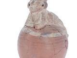a small vase with a monkey sitting on top of it