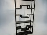 a black bookcase with three shelves and a lamp on top of it