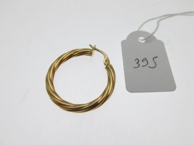 un gros plan sur une paire de boucles d'oreilles créoles en or avec une étiquette de prix