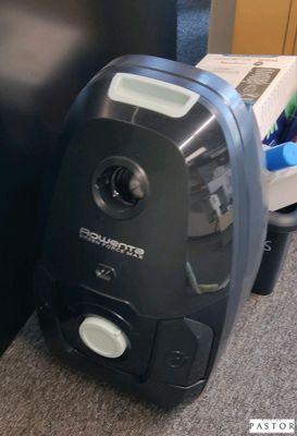 un aspirateur noir et blanc posé par terre près d'un mur noir