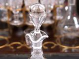a glass decanter on a table with glasses in the background